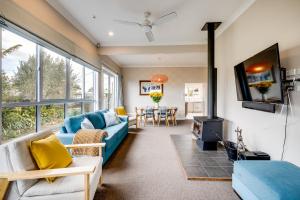 a living room with a blue couch and a tv at Serenity by the Sea - Haumoana Beach Holiday Home in Haumoana