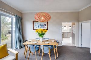 a dining room with a table and a vase of flowers at Serenity by the Sea - Haumoana Beach Holiday Home in Haumoana