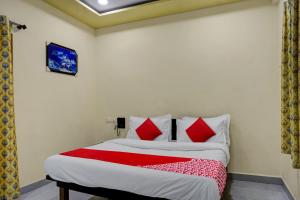 プネにあるHotel Royal Innのベッドルーム1室(赤と白の枕が備わるベッド1台付)