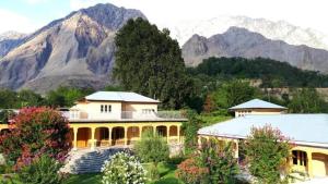 una gran casa amarilla con montañas en el fondo en Ghairaat Castles, en Chitral