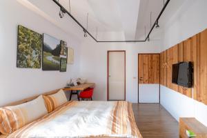 安平的住宿－RE+Wood民宿，一间卧室配有一张床、一张书桌和一台电视。