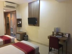 a hotel room with two beds and a desk and a tv at University Club (UC) Hotel UGM in Yogyakarta