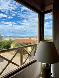 a lamp in front of a window looking out at the ocean at El Mirador, Apartamento in Punta Del Diablo