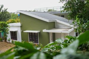 a green and white building with black shutters at B'camp Resorts & Homestays in Wayanad