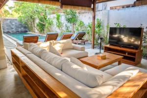 uma sala de estar com um sofá grande e uma televisão em Kelapa Villas em Gili Trawangan