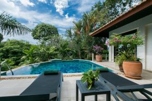 a pool with a table and chairs next to a house at Katamanda Villa Chanti in Kata Beach