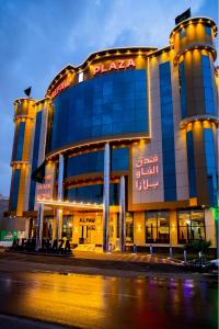 un grand bâtiment avec des panneaux de néon devant lui dans l'établissement HOTEL ALFAW PLAZA, à Sharurah