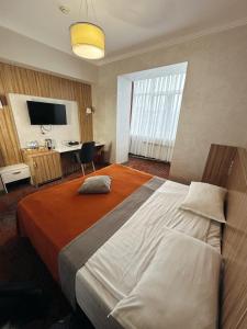 a hotel room with a large bed and a desk at Mildom Premium Hotel in Almaty