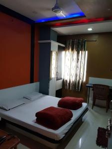 1 dormitorio con 1 cama con 2 almohadas rojas en New Hotel Shree Radha Krishna Palace, Maheshwar en Maheshwar