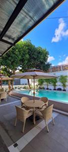 a patio with a table and chairs and an umbrella at Hotel Carmelita in Tuguegarao City