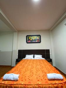 een slaapkamer met een groot oranje bed met 2 kussens bij HOTEL BROMELIAS in Tarapoto