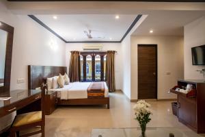 a bedroom with a bed and a table in a room at Goa Villagio Resort & Spa - A unit of IHM in Betalbatim