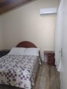 a bedroom with a bed with a wooden headboard and a table at Sobrado recanto som das águas in Santo Amaro da Imperatriz