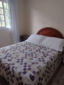 a bed with a quilt on it in a bedroom at Sobrado recanto som das águas in Santo Amaro da Imperatriz