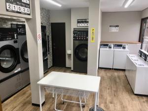 a laundry room with three washing machines and a white table at Guest House Matsu in Osaka