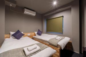 dwa łóżka w pokoju z dużym ekranem w obiekcie BESTIE by DOYANEN w Osace