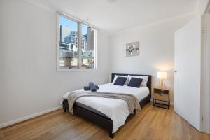 - une chambre blanche avec un lit et une fenêtre dans l'établissement Vintage Charm 2 Bed Apt Near Flinders Station, à Melbourne