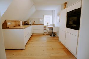 a kitchen with white cabinets and a wooden floor at Lenis Lieblingsplatz in Rietberg