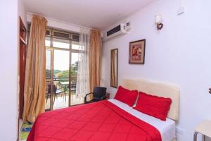 a bedroom with a red bed and a balcony at Frontiers Hotel & Conference Entebbe in Entebbe