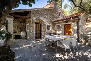 a stone house with a table and chairs on a patio at STONE HOUSE reTREAT in Mali Lošinj