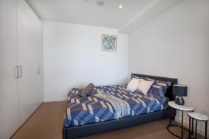 - une chambre avec un lit avec une couette bleue et 2 tables dans l'établissement Marvellous 2-Bed High-Rise: Amazing Views, Free Parking, à Melbourne 7 autres photos