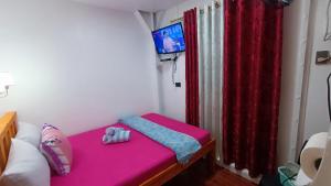 マニラにあるMJ Homeのピンクベッド1台、赤いカーテンが備わる小さな客室です。