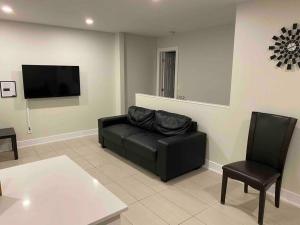 a living room with a black couch and a tv at 3 Bedroom Home, 3 Queen Beds, Close To All Amenities in Ottawa