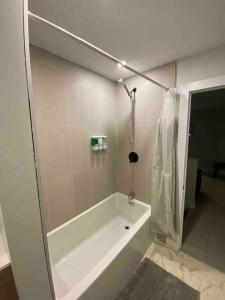 a white bathroom with a tub and a shower at 3 Bedroom Home, 3 Queen Beds, Close To All Amenities in Ottawa