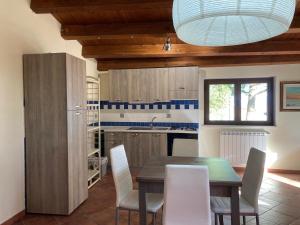 cocina con mesa de madera y sillas blancas en Casetta Perseo, en Cammarata