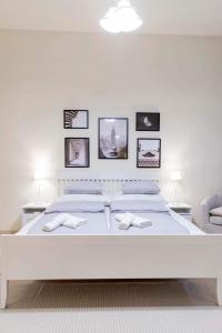 Dormitorio blanco con cama blanca y cuadros en la pared en Sweet Relax House, en Budapest