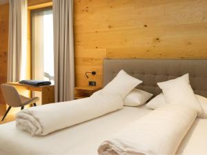 a bedroom with a bed with white pillows and a desk at My Heimat 1495 Arlberg in Schröcken