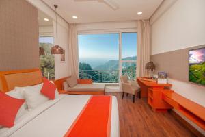 a bedroom with a bed and a desk and a large window at Yog Wellness Resort & Spa By Amritara in Mussoorie