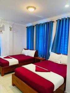 貢布的住宿－Kim Chua Guest House，配有蓝色窗帘的客房内的两张床