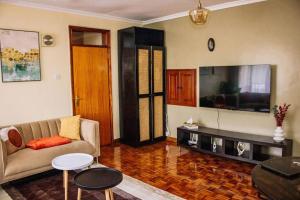sala de estar con sofá y TV de pantalla plana en The happy place - Westlands, Nairobi en Nairobi