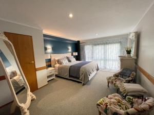 a bedroom with a bed and a chair and a mirror at Tikitere Lodge, Rotorua in Rotorua