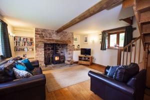a living room with two leather couches and a stone fireplace at Cabalva Mill Cottage - very private and with views over the River Wye in Clifford