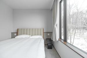 a bedroom with a bed and a large window at Villa Yin Niseko in Kutchan