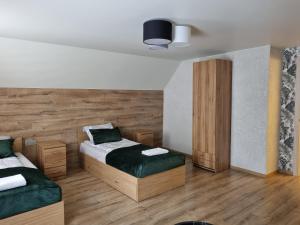 two beds in a room with wooden floors at Akmerenta - Kadagių dvarelis in Akmenė