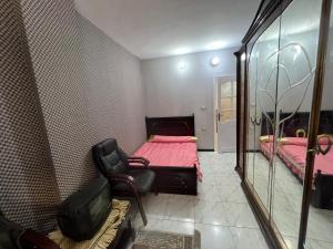 1 dormitorio con cama, silla y espejo en شقه حديثه في وسط المنصوره بالقرب من الجامعه ١٧٥ متر en Mansoura