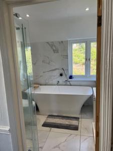 una vasca bianca in un bagno con finestra di sandown cottage in esher a Esher