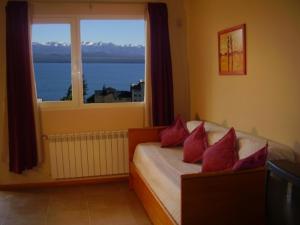 a bedroom with a bed with red pillows and a window at Departamentos Altos del Centro in San Carlos de Bariloche