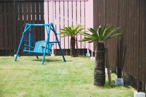 a blue swing in a yard with two palm trees at Little Seagull by SANA in Tateyama