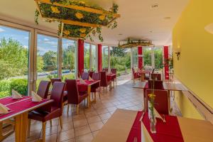 un restaurante con mesas y sillas rojas y ventanas en KIShotel am Kurpark, en Bad Soden-Salmunster