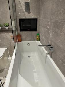 a bathroom with a tub with a tv on the wall at Bedroom 1 in Elegant 3 Bed Flat in Ramsgate in Kent