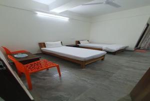 a room with two beds and a table and a chair at Hotel YLS, Itnagar in Itānagar