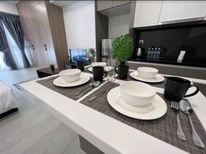 a table with plates and utensils in a kitchen at 2Bed For 4 // KLIA Sepang Xiamen University in Sepang