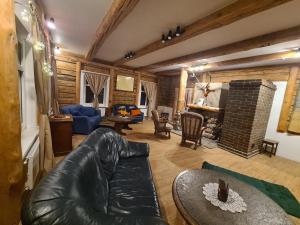 a living room with a leather couch and a fireplace at Zirgu sēta "Klajumi" - Horse ranch "Klajumi" in Kaplava