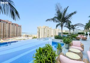 a large swimming pool with chairs and palm trees at bnbmehomes - Lux Studio Retreat in Palm Jumeirah - 2016 in Dubai