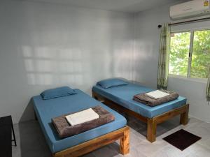 two beds in a room with a window at เมี่ยงไม้ รีสอร์ท in Ban Khlong Khen