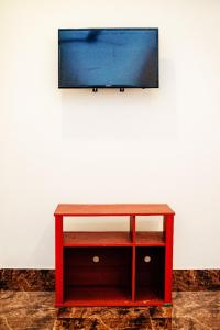 einen roten Tisch mit einem TV an der Wand in der Unterkunft Villa Andaz in Negombo